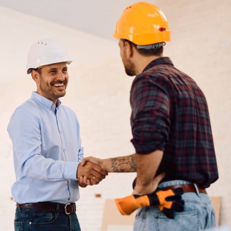 two men wearing hard hats shaking hands