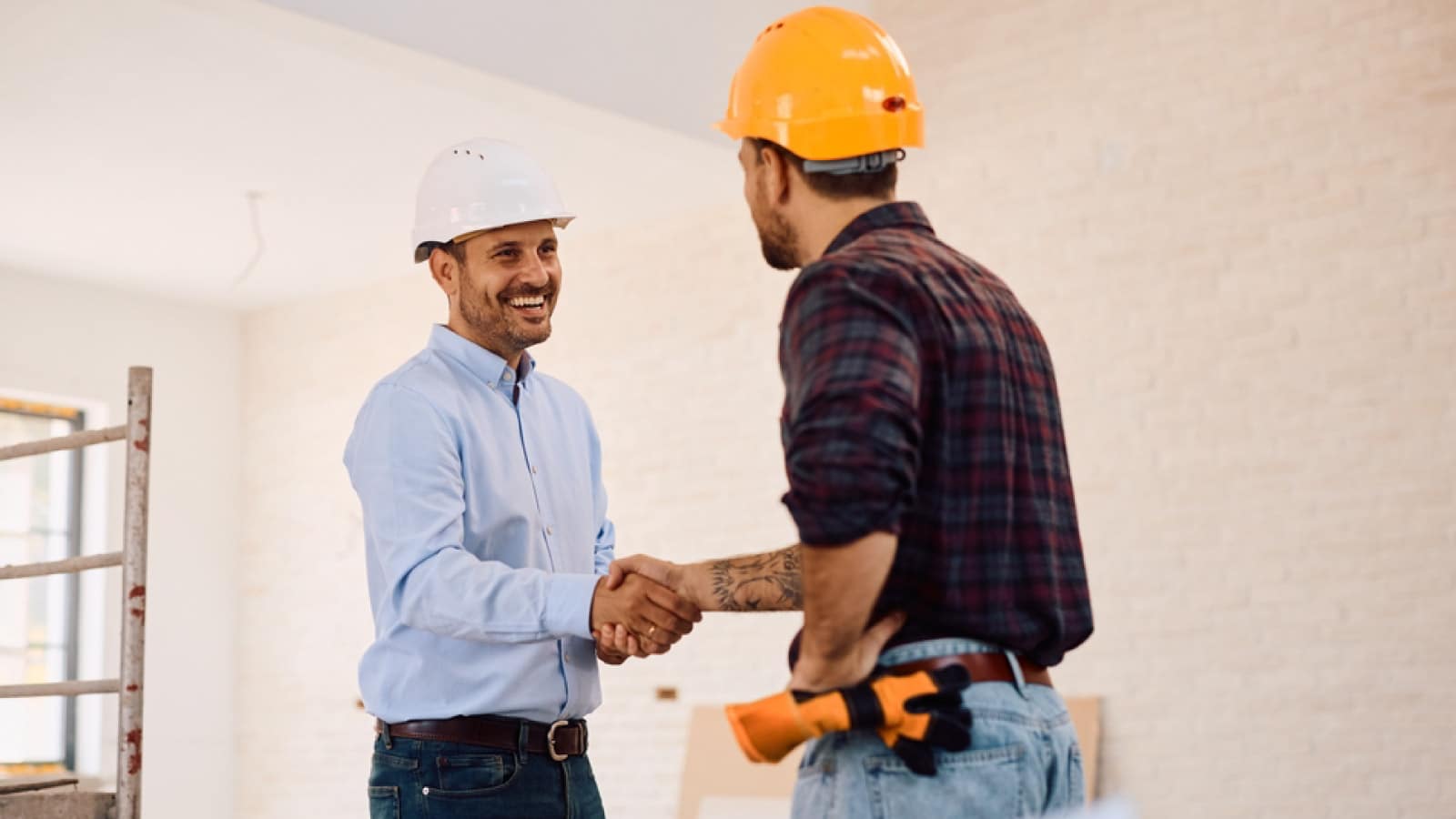 two men wearing hard hats shaking hands